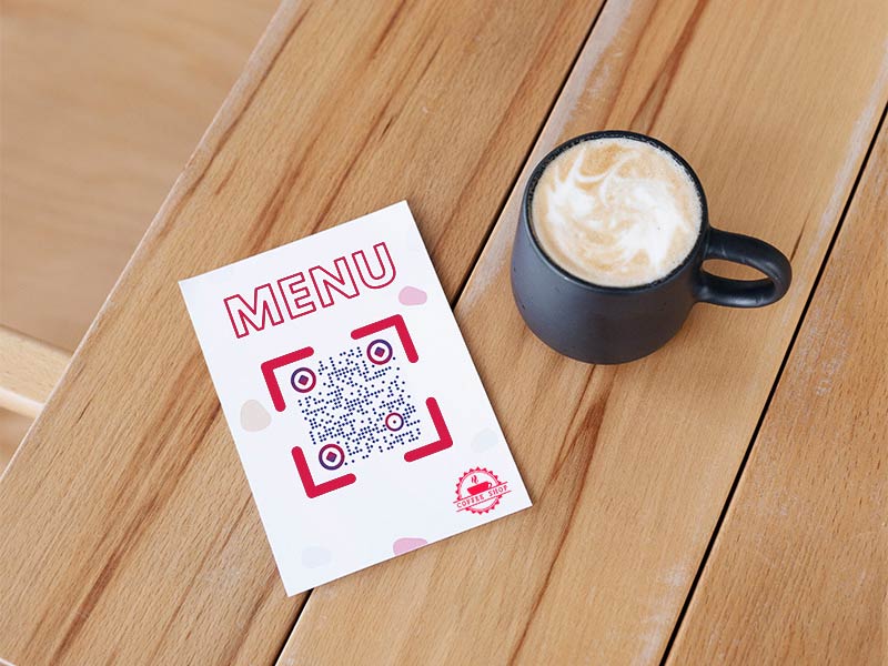 Código QR PDF en una mesa cerca de una taza de café en una cafetería