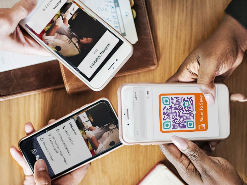 Inimesed istuvad laua taga ja jagavad oma digitaalse visiitkaardi QR-koodi
