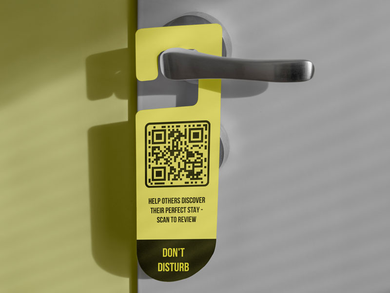 Código QR de Tripadvisor en la puerta de una habitación de hotel con huéspedes escribiendo reseñas